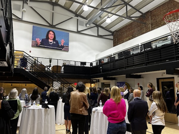 Alumnae gathered at the Philadelphia Evening of Excellence as President Neeli Bendapudi addresses the room on screen