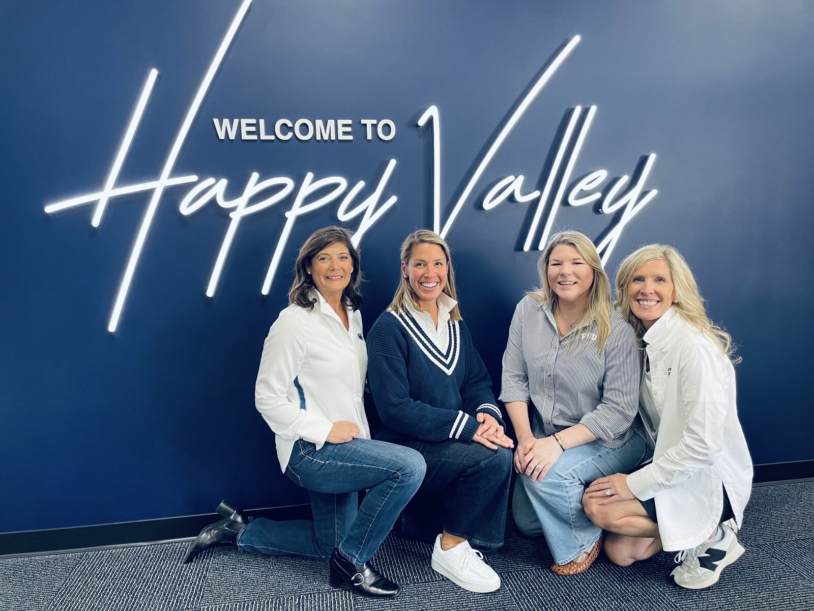 Alumnae panel speakers gathered at the “Welcome to Happy Valley” sign